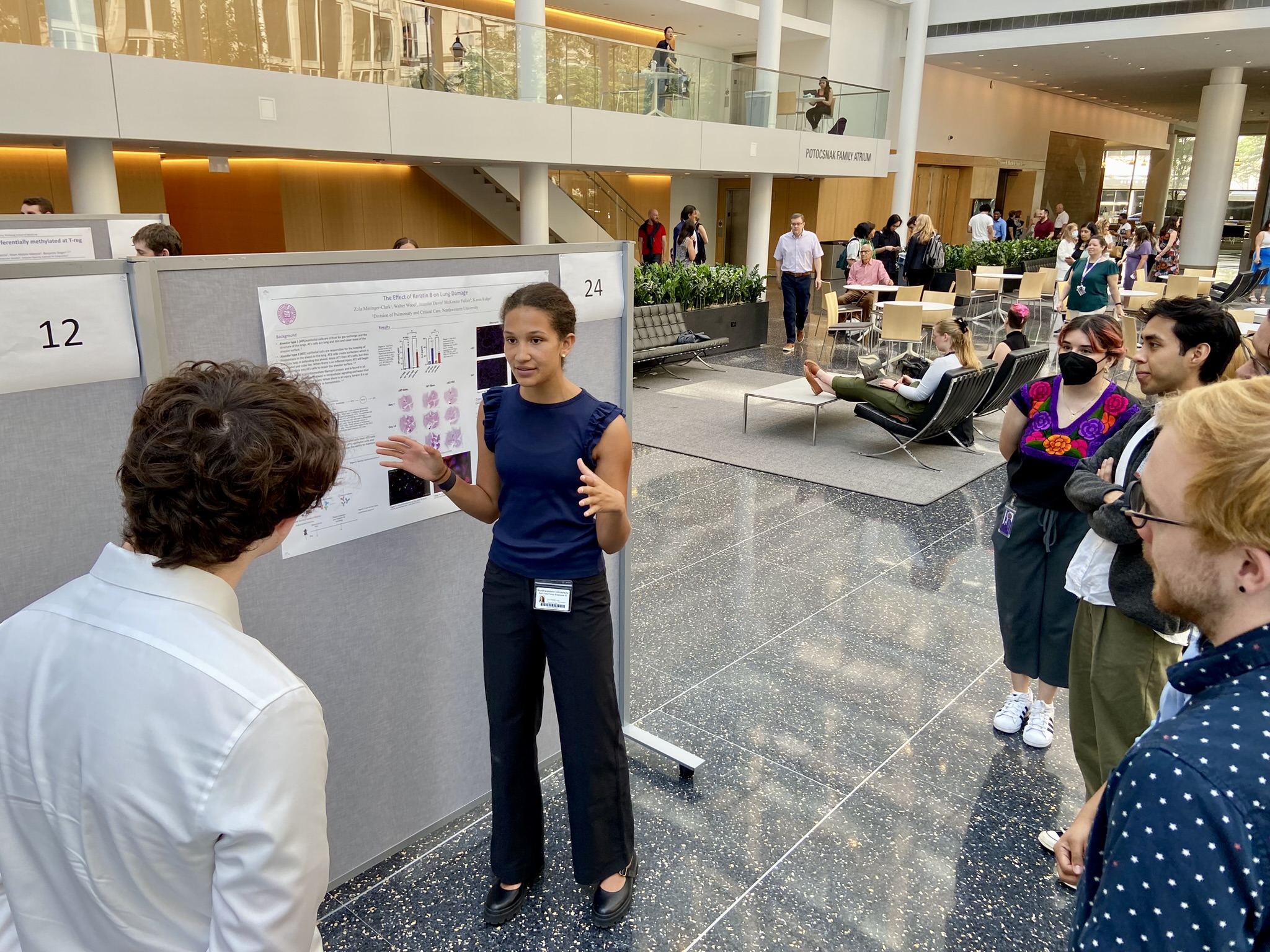 An intern explains her project while presenting her poster at the Kimberly Querrey Summer Research Symposium